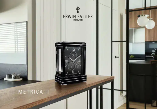 ERWIN SATTLER METRICA II.
Leverbaar in zwart gelakt of in Notenhout beide hoogglans gepolijst met metaal inleg, 27,5 cm hoog, 18,50 cm breed en 12 cm diep. Ontspiegeld mineraal glas. Uurwerk Sattler Kaliber 1385. Loopduur 15 dagen. Veer opwinding voorzien van een via een Schneck geregelde krachtsoverbrenging. Regelbaar Zwitsers Echappement. 12 Precisie kogellagers en 11 Robijn lagers. Wijzerplaat in zwart of zilver met datum aanduiding, gangreserve en seconde wijzer. Staal gepolijste wijzers bij de zwarte wijzerplaat of geblauwd stalen wijzers bij de zilveren wijzerplaat. 